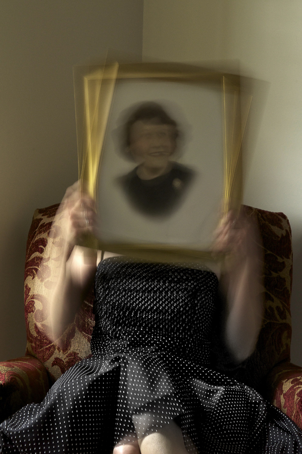 Holding a photo of my grandmother while sitting in her mother's chair.